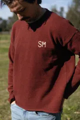 Sweater de punto color bordó con cuello redondo, mangas largas y diseño holgado. Cuenta con las iniciales "SM" bordadas en hilo crudo en el pecho.