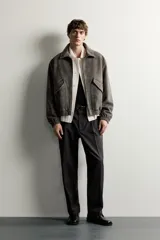Cazadora de hombre regular fit confeccionada en tejido efecto ante, con acabado lavado, cuello solapa, manga larga, bolsillos de plastrón con solapa en la cadera, detalles elásticos en puños y cintura, y cierre frontal de cremallera.