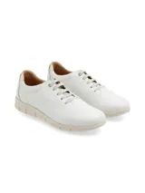 Sneakers de cuero blanco con detalles dorados en el talón, cordones planos y suela anatómica de goma color beige.