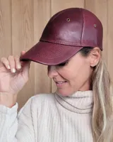 Gorra tipo visera confeccionada en cuero color bordó, con ojales metálicos de ventilación y costuras reforzadas en la visera.