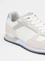 Championes urbanos Rusty modelo Nour, de diseño deportivo con paneles en tonos gris claro, blanco y detalles en celeste. Confeccionados en una combinación de materiales sintéticos y gamuza, cuentan con cordones frontales y suela de goma con relieve.