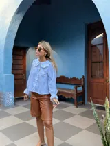 Bermuda de cuero sintético en color marrón, con diseño de corte recto, tiro medio y costuras verticales decorativas en el frente.