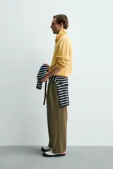 Sudadera de corte relajado confeccionada en algodón con interior de rizo, color amarillo mostaza con efecto lavado. Presenta cuello subido con cierre frontal de cremallera y detalle de cinta trenzada en el tirador, manga larga y acabados en rib.