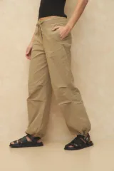 Pantalón babucha tipo parachute color beige, de nylon, con cordones ajustables en la cintura y en los tobillos.