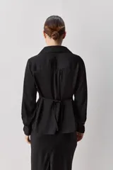 Camisa blanca de manga larga con textura suave y caída liviana, cuello camisero, puños anchos y fruncidos sutiles en los hombros.