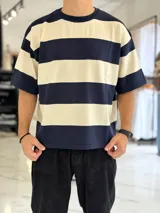 Remera de punto a rayas horizontales en tonos azul marino y beige, de manga corta y corte oversize. Presenta un gran número 15 rojo estampado en la espalda.