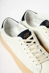 Zapatillas blancas de cuero con detalles en negro en el talón y la lengüeta.