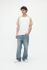 Remera estilo raglán color blanco en el cuerpo con mangas cortas color arena y cuello redondo marrón. Presenta un pequeño bordado en el pecho.