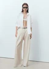 Pantalón wide leg de tiro medio con diseño de rayas sutiles, pinzas delanteras, bolsillos laterales y de ribete en la parte posterior. Cuenta con cierre de gancho y cremallera, y trabillas para cinturón.