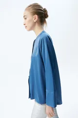 Camisa color crema de satén con botones forrados, cuello en V y manga acampanada tres cuartos.