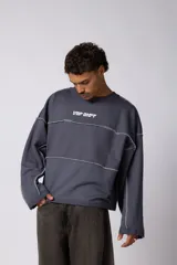 Buzo oversize de corte boxy, confeccionado en algodón rústico de alto gramaje en color beige. Presenta cuello redondo con borde crudo, mangas largas y una estampa frontal con el texto VCP delimitado por líneas horizontales blancas.