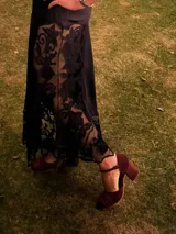 Zapato de tacón color bordó, confeccionado en terciopelo suave, con diseño de pulsera en el tobillo y cierre de hebilla. La punta es cerrada y presenta detalles de líneas cosidas. El tacón es ancho y forrado, con una altura de 7 cm.