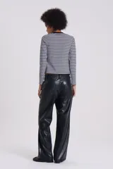 Pantalón de cuero sintético negro, estilo jeanero con tiro bajo, corte recto/flare y bolsillos delanteros y traseros.