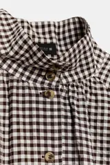 Chaqueta de manga larga con estampado de cuadros vichy en tonos marrón y blanco, cuello camisero, cierre frontal con botones y bajo ajustable con cordón.