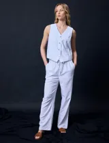 Pantalón de lino de corte recto y tiro medio, con pretina elástica ancha y lazo de ajuste frontal. Presenta bolsillos laterales verticales y bolsillos traseros.