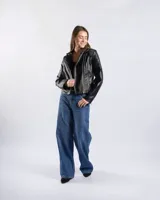 Campera estilo motero de símil cuero color negro, con cuello alto, cierre frontal asimétrico, bolsillos con cierre y detalles acolchados en los hombros.