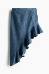 Pollera midi de denim de algodón rígido, con diseño asimétrico, tiro medio, pinzas en la cintura y volado con volumen en el borde inferior.