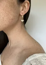 Aros colgantes dorados con forma de concha marina, con circonitas y perla de río lila.