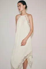 Vestido largo ZARA Woman Collection confeccionado en hilatura de viscosa de color crudo, con cuello halter, tirantes finos, detalles de encaje a tono y bajo asimétrico.