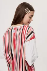 Remera oversize de manga corta con diseño de rayas verticales en tonos rojos, negros, blancos y tostados, y mangas blancas lisas.