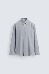 Camisa de corte regular fit confeccionada en tejido de algodón con diseño de rayas verticales. Presenta cuello abotonado, manga larga con puños abotonados y cierre frontal de botones.