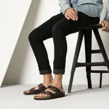Sandalias Birkenstock modelo Arizona, color marrón oscuro, con doble tira ajustable con hebillas metálicas y plantilla anatómica de corcho.