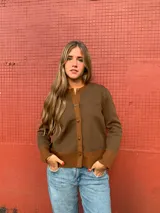 Cárdigan marrón de lana merino con cuello redondo, cierre frontal con botones y ribete en contraste color marrón claro en cuello, puños y ruedo.