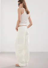 Jeans de tiro alto y diseño balloon en color blanco, con estilo vaquero, trabillas para cinturón, cinco bolsillos tradicionales y cierre frontal de botón y cremallera.