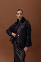 Chaqueta de cuero ovino con efecto gastado, estilo jeanero, con cierre frontal de botones metálicos y bolsillos frontales. Posee mangas largas con puños y un cuello desmontable de corderito negro.