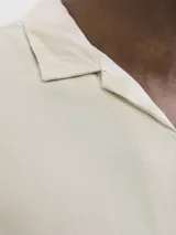 Camisa de manga corta con cuello resort, confeccionada en viscosa fluida con cierre frontal de botones y corte relajado.