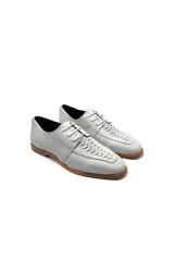 Zapatos acordonados de cuero color blanco con detalle de trenzado en la parte delantera.