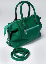 Cartera de mano color verde esmeralda de cuero sintético, con cierre superior y bolsillo frontal con cierre. Incluye correa larga extraíble y doble asa de mano.