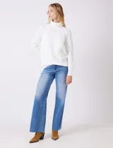 Polera de punto grueso color blanco, con cuello alto, mangas largas de corte ranglan y diseño de texturas combinadas.