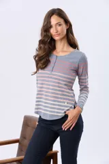 Remera de manga larga con cuello redondo y cierre frontal parcial con botones. Presenta un diseño de rayas horizontales en tonos pastel sobre una base beige, con aberturas laterales en el ruedo.