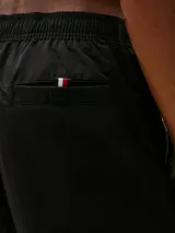 Short de baño Tommy Hilfiger de corte amplio, con diseño color block que incorpora los colores icónicos de la marca (negro, blanco, azul marino y rojo) en la parte frontal. Cuenta con cintura elástica con cordón ajustable, dos bolsillos laterales y un bolsillo trasero de ojal.