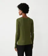 Suéter de punto color rosado, con cuello barco, mangas largas y puños con botones decorativos. El dobladillo también es acanalado.