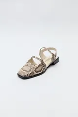 Zuecos destalonados color crema, de símil cuero, con punta cuadrada y finas tiras con hebillas ajustables. Cuentan con taco de 2,5cm de alto.