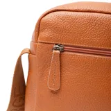 Bandolera de cuero color habano con textura granulada, cierre superior y bolsillo frontal abierto. Cuenta con una correa de tela ajustable con detalle de marca grabado.