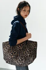 Bolso tipo shopper con estampado animal print de leopardo, con asas largas de hombro en color negro, bolsillo interior con cierre y cierre superior mediante imán.