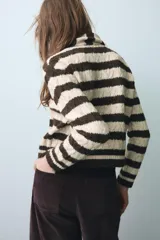 Chaqueta de punto a rayas horizontales en color marrón y beige, con cuello redondo, manga larga y cierre frontal con botones. Incluye una bufanda integrada del mismo tejido y diseño.