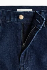 Jean de denim azul oscuro con tiro alto, piernas rectas y pliegues marcados al frente y en la espalda. Cuenta con cierre de botón y bolsillos delanteros insertados.