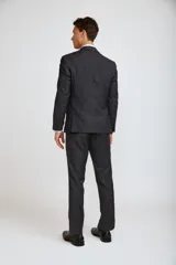 Traje de tres piezas compuesto por saco, chaleco y pantalón de corte sastre. El conjunto presenta un diseño en color gris oscuro con un sutil patrón de cuadros gales, ideal para eventos formales.