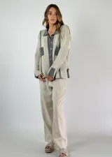 Saco de punto color naranja con detalles de rayas horizontales en las mangas y franjas verticales en el cuerpo. Tiene cuello tipo polo, cierre frontal con botones y un bolsillo decorativo en el pecho.