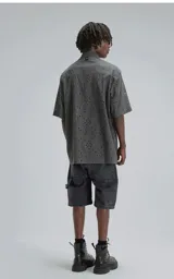 Camisa de manga corta con calce oversize, confeccionada en algodón con bordado tipo broderie y acabado con efecto desgastado. Presenta cuello clásico y cierre frontal con botones.