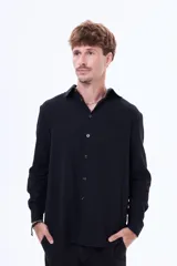 Camisa de manga larga color negro, con cuello clásico, cierre frontal con botones y bolsillo en el pecho.