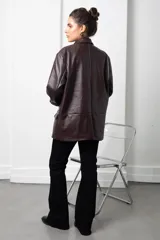 Blazer de eco cuero color bordó, con diseño oversize, hombreras estructuradas y solapas clásicas. Presenta mangas largas con puños vueltos y cierre frontal con botón.