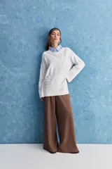 Sweater blanco de punto con diseño holgado, cuello redondo, mangas largas acampanadas y detalles de textura horizontal en el tejido.