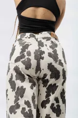Pantalón wide leg con estampado de vaca en blanco y negro, de tiro alto y cierre de botón y cremallera.