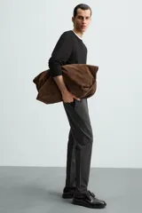 Pantalón de corte slim fit confeccionado en tejido elástico, con cintura elástica, cierre frontal con cremallera y botón, bolsillos laterales y bolsillos traseros de vivo.