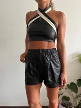 Top halter de cuero sintético negro con tiras cruzadas al cuello en color blanco.